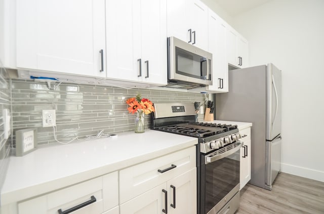 kitchen featuring white cabinetry, light wood-type flooring, stainless steel appliances, and backsplash