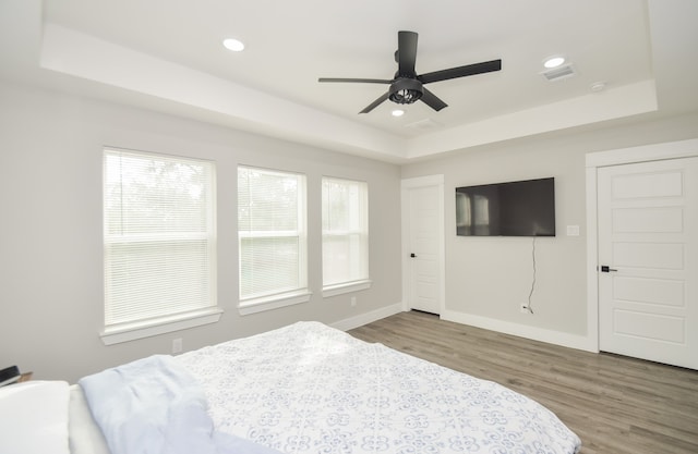 bedroom featuring hardwood / wood-style flooring, ceiling fan, and a raised ceiling