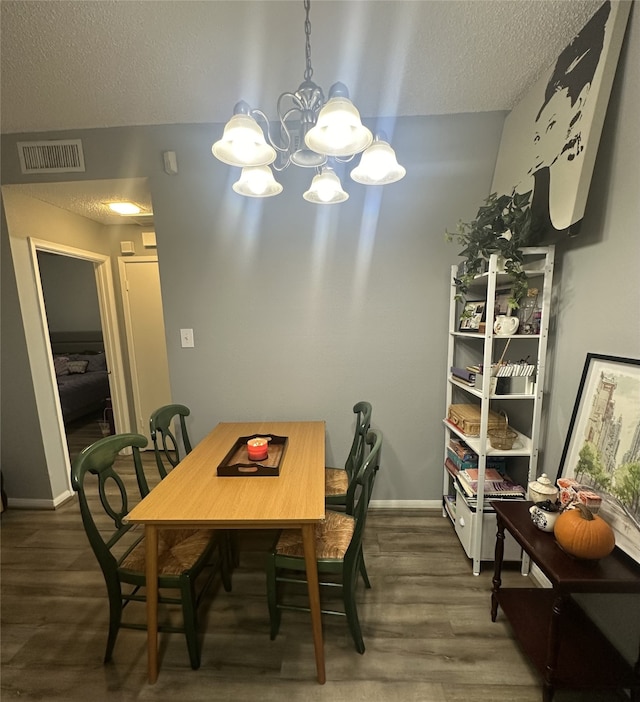 dining area with a textured ceiling, dark hardwood / wood-style flooring, and a chandelier