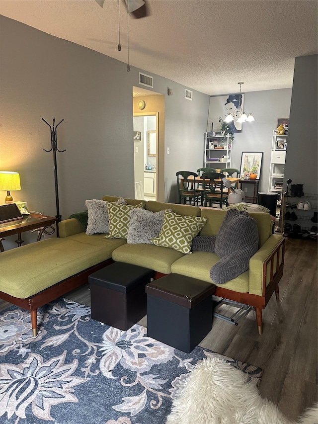 living room featuring ceiling fan with notable chandelier, a textured ceiling, and dark hardwood / wood-style flooring