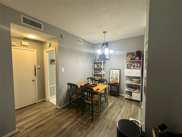 dining room with hardwood / wood-style floors, a textured ceiling, and a notable chandelier