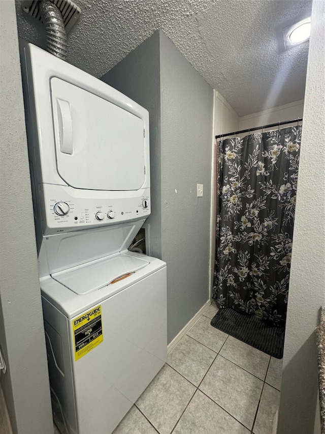 laundry room with a textured ceiling, stacked washer and dryer, and light tile patterned floors