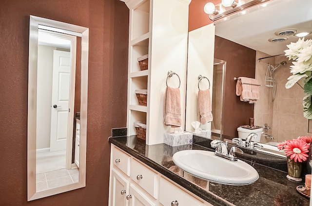 bathroom featuring toilet, built in features, vanity, and tiled shower