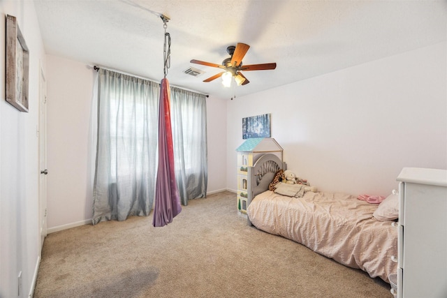 bedroom featuring ceiling fan, light colored carpet, and a textured ceiling