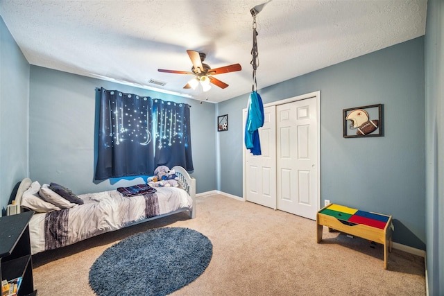 bedroom with a textured ceiling, carpet floors, a closet, and ceiling fan