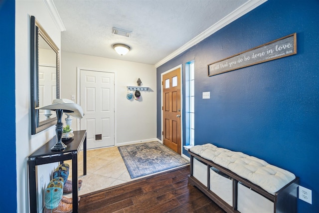 entryway with hardwood / wood-style floors, ornamental molding, and a textured ceiling