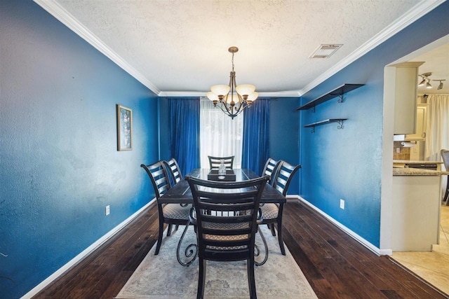 dining space featuring a notable chandelier, hardwood / wood-style flooring, ornamental molding, and a textured ceiling