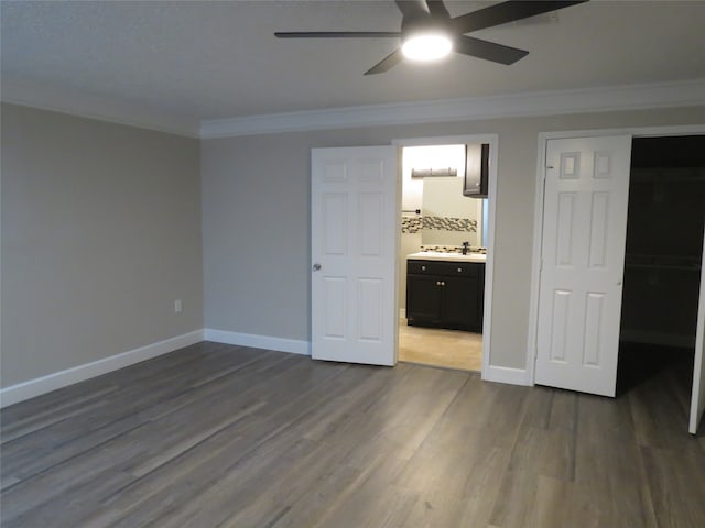 unfurnished bedroom with dark wood-type flooring, connected bathroom, ornamental molding, ceiling fan, and a closet