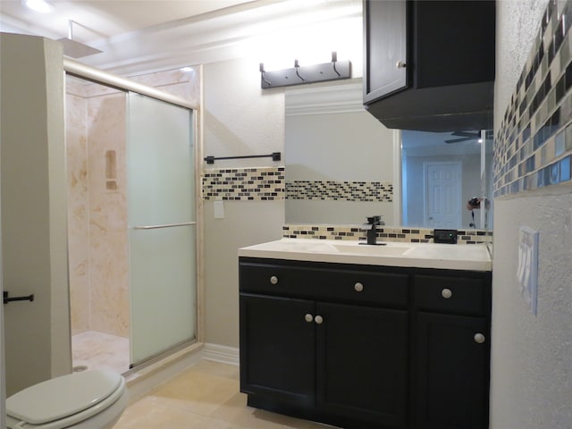 bathroom featuring a shower with door, vanity, tile patterned floors, toilet, and decorative backsplash