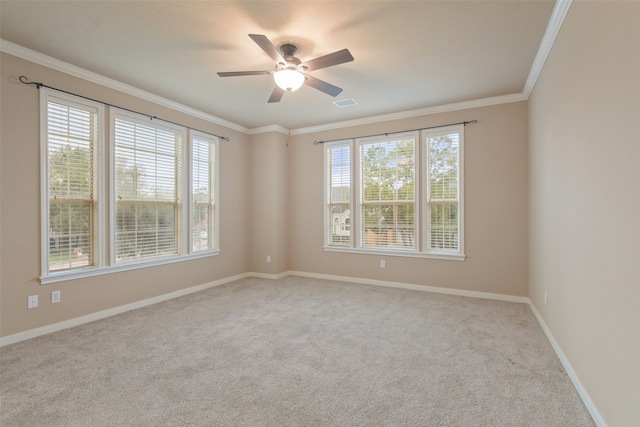 spare room with ceiling fan, a wealth of natural light, light colored carpet, and crown molding