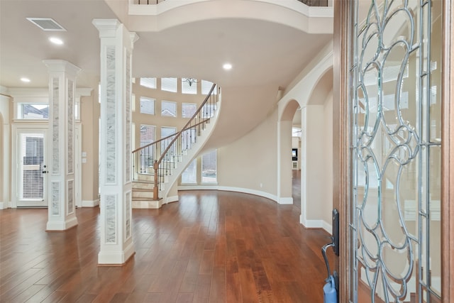 foyer with plenty of natural light, dark wood-type flooring, and decorative columns