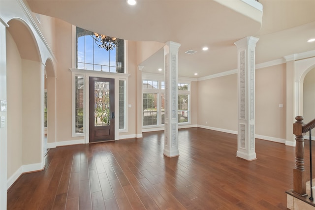 foyer featuring dark wood-type flooring, a chandelier, a healthy amount of sunlight, and decorative columns