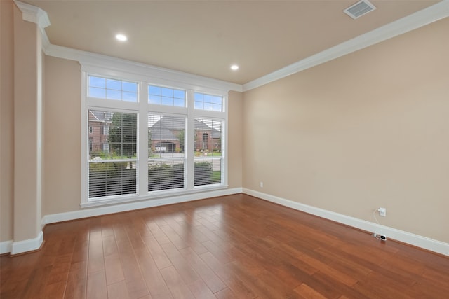 empty room featuring wood-type flooring and crown molding