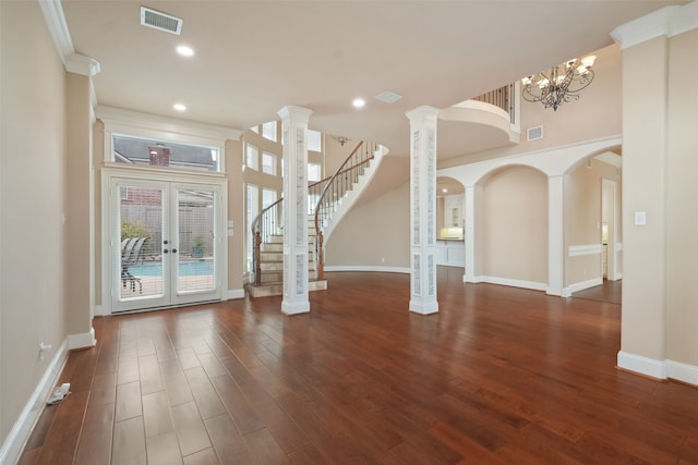 unfurnished living room featuring french doors, ornamental molding, dark hardwood / wood-style flooring, decorative columns, and a chandelier