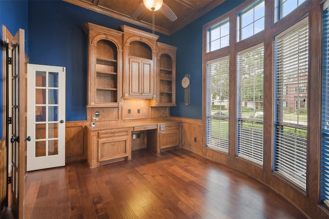 unfurnished office with dark wood-type flooring, built in desk, ceiling fan, and ornamental molding