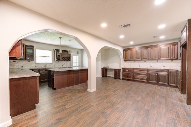 kitchen featuring backsplash, decorative light fixtures, dark brown cabinets, a textured ceiling, and dark hardwood / wood-style flooring