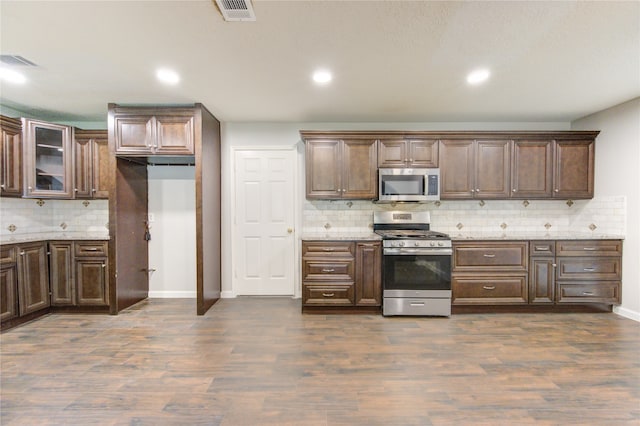 kitchen featuring dark hardwood / wood-style flooring, dark brown cabinets, backsplash, and appliances with stainless steel finishes