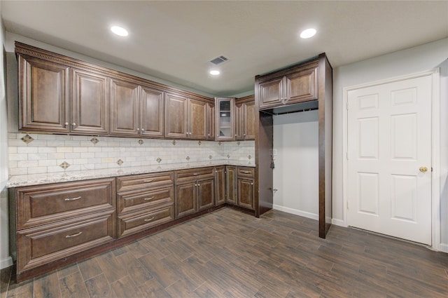 kitchen with dark brown cabinetry, light stone countertops, dark hardwood / wood-style floors, and decorative backsplash