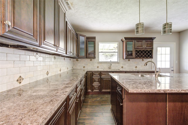 kitchen featuring pendant lighting, dark hardwood / wood-style flooring, sink, and tasteful backsplash