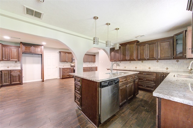 kitchen featuring dark hardwood / wood-style flooring, dishwasher, sink, an island with sink, and pendant lighting