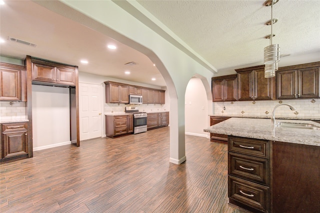 kitchen with dark hardwood / wood-style flooring, backsplash, appliances with stainless steel finishes, and sink