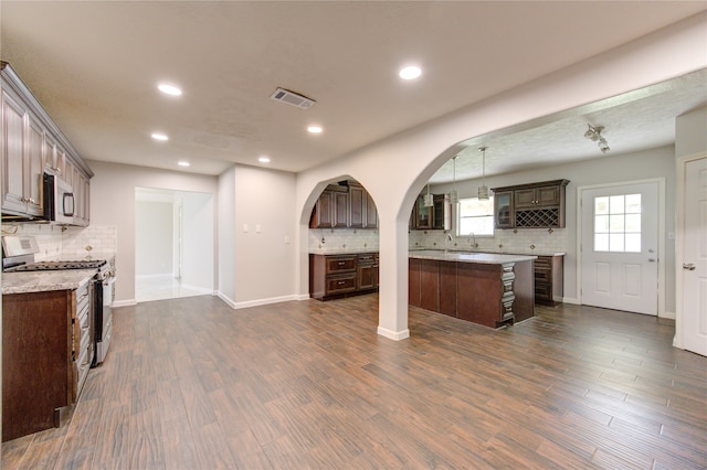 kitchen featuring dark wood-type flooring, dark brown cabinets, appliances with stainless steel finishes, and a center island