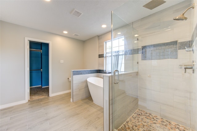 bathroom with shower with separate bathtub and wood-type flooring