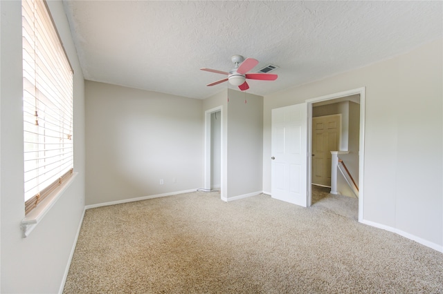 spare room featuring light carpet and a textured ceiling