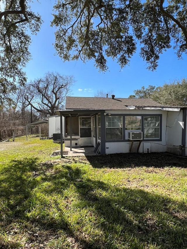 rear view of property with cooling unit and a yard