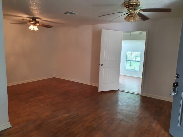 empty room with ceiling fan, a textured ceiling, and dark hardwood / wood-style flooring