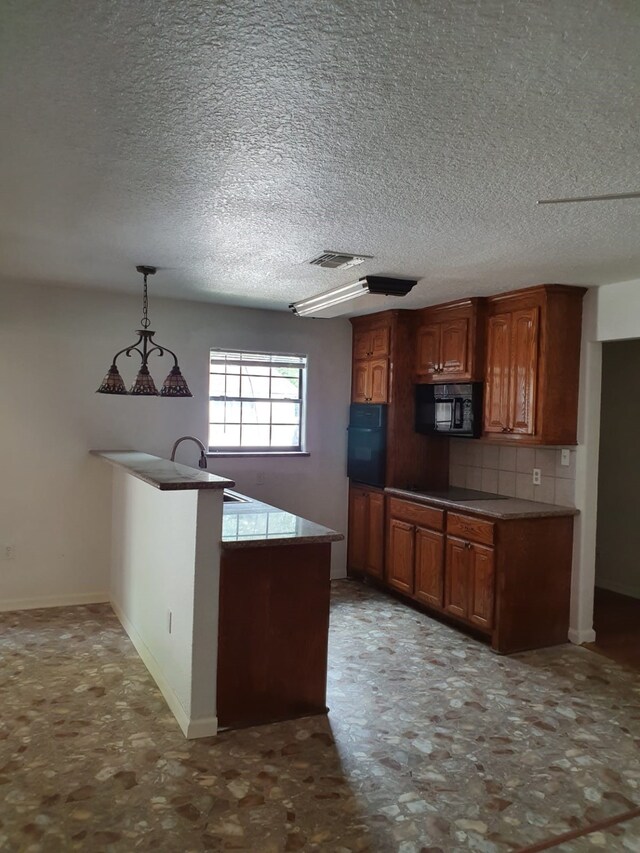 kitchen with kitchen peninsula, hanging light fixtures, black appliances, a textured ceiling, and backsplash