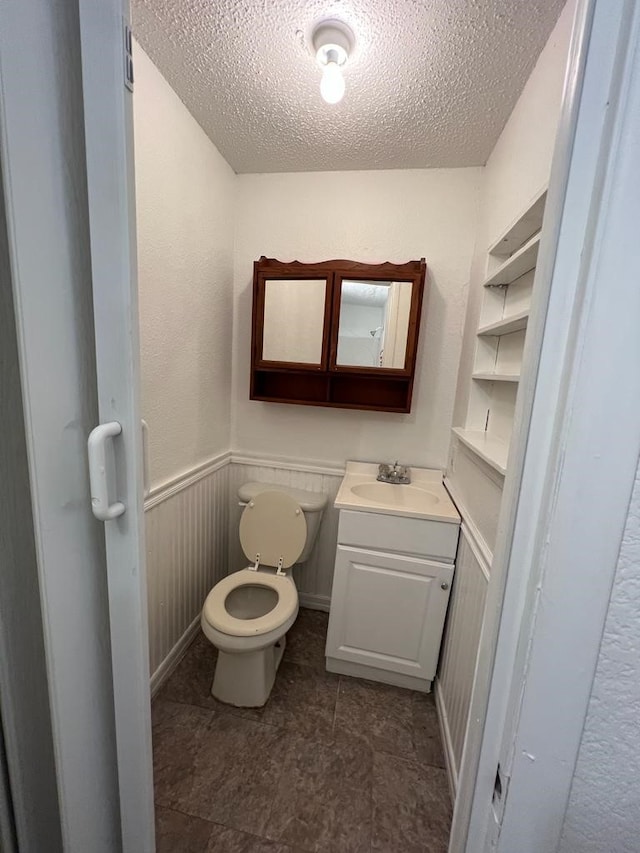 bathroom with vanity, a textured ceiling, and toilet