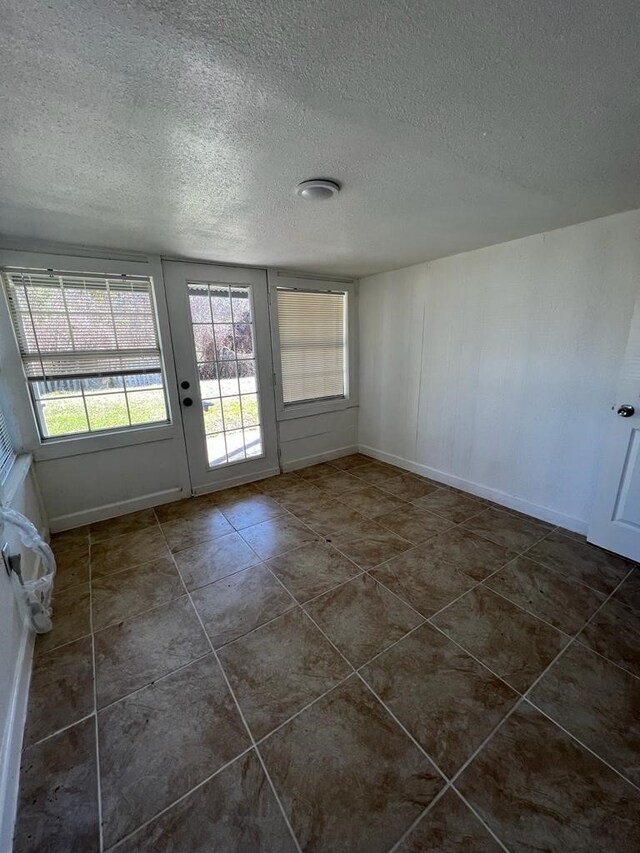 empty room with a textured ceiling and dark tile patterned floors