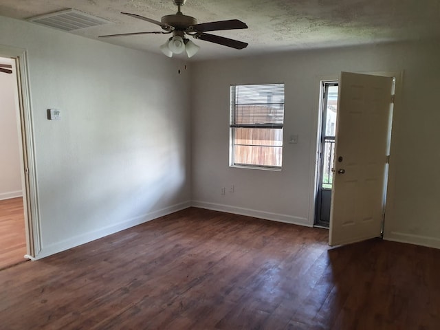 empty room featuring dark hardwood / wood-style flooring, a textured ceiling, and ceiling fan