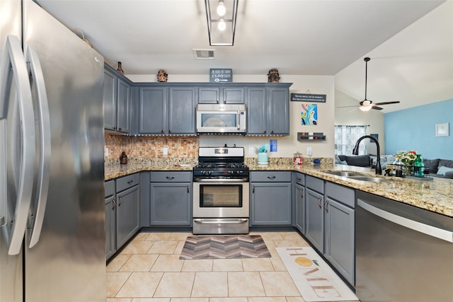 kitchen with ceiling fan, sink, stainless steel appliances, light stone counters, and vaulted ceiling