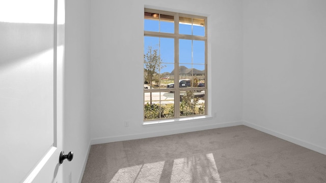 carpeted empty room featuring baseboards