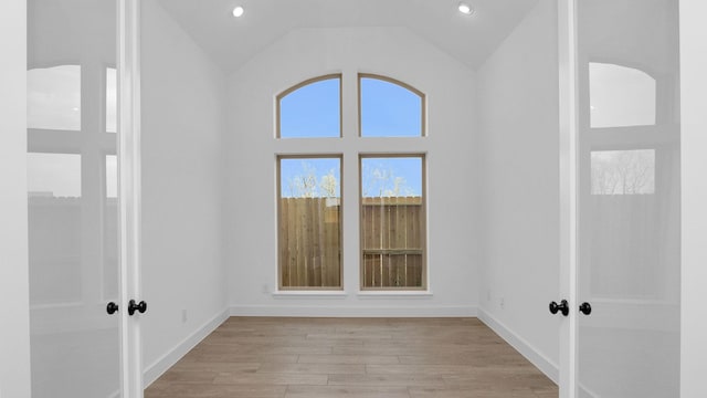 unfurnished room featuring light wood-style floors, recessed lighting, vaulted ceiling, and baseboards