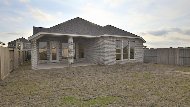 back of house with a patio, brick siding, roof with shingles, and a fenced backyard