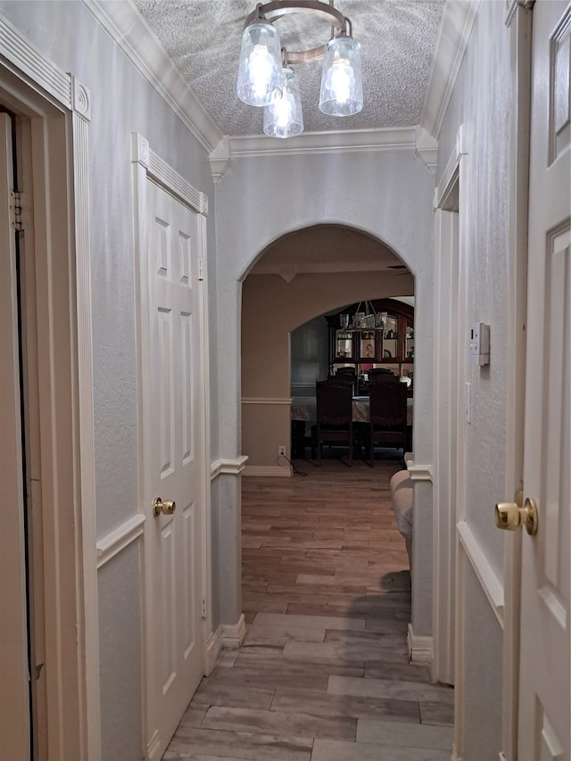 hall featuring ornamental molding, a textured ceiling, and hardwood / wood-style flooring