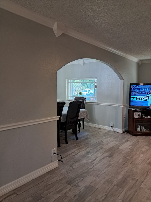 dining area featuring hardwood / wood-style floors, a textured ceiling, and ornamental molding