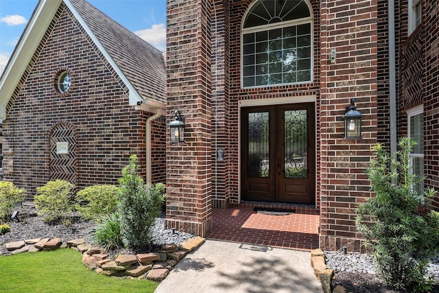 view of exterior entry featuring brick siding and french doors