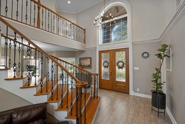 foyer entrance with french doors, light hardwood / wood-style flooring, a wealth of natural light, and a high ceiling