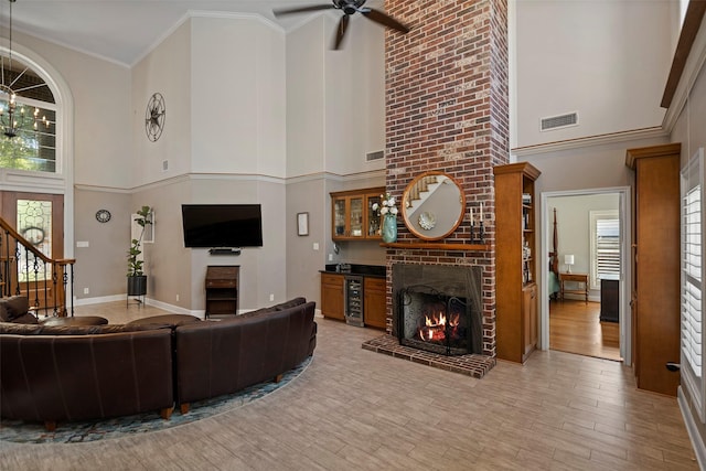 living room with a high ceiling, light hardwood / wood-style flooring, a brick fireplace, and a wealth of natural light