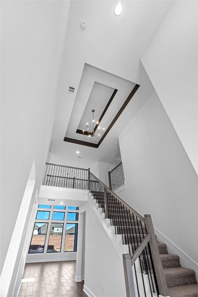 staircase featuring tile patterned floors, an inviting chandelier, and a high ceiling