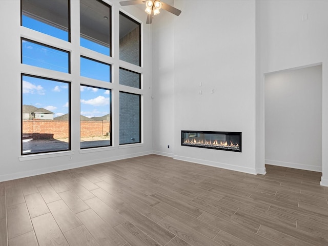 unfurnished living room featuring ceiling fan and a high ceiling