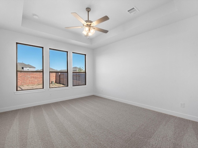 unfurnished room with a tray ceiling, ceiling fan, and carpet flooring