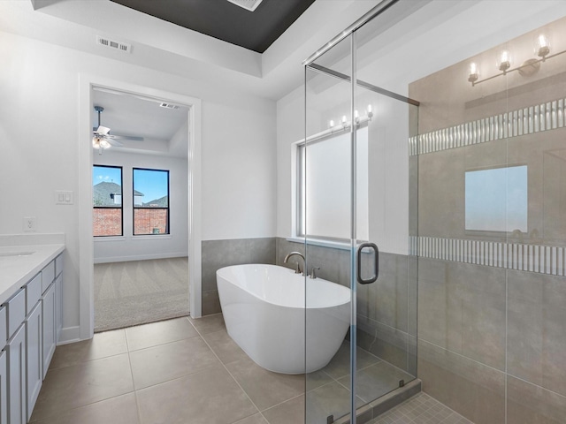 bathroom featuring vanity, tile patterned flooring, ceiling fan, separate shower and tub, and a tray ceiling