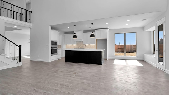 kitchen with a center island with sink, white cabinetry, appliances with stainless steel finishes, and light hardwood / wood-style flooring