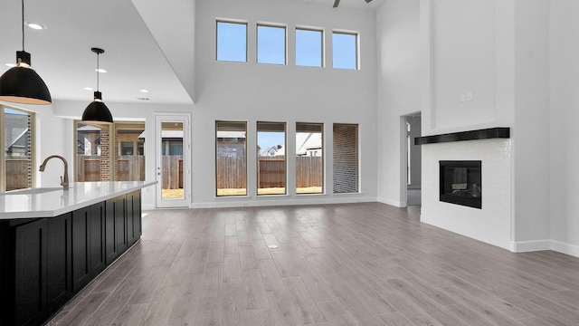 unfurnished living room with a wealth of natural light, hardwood / wood-style flooring, a high ceiling, and sink