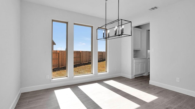 unfurnished dining area with a notable chandelier and dark hardwood / wood-style floors